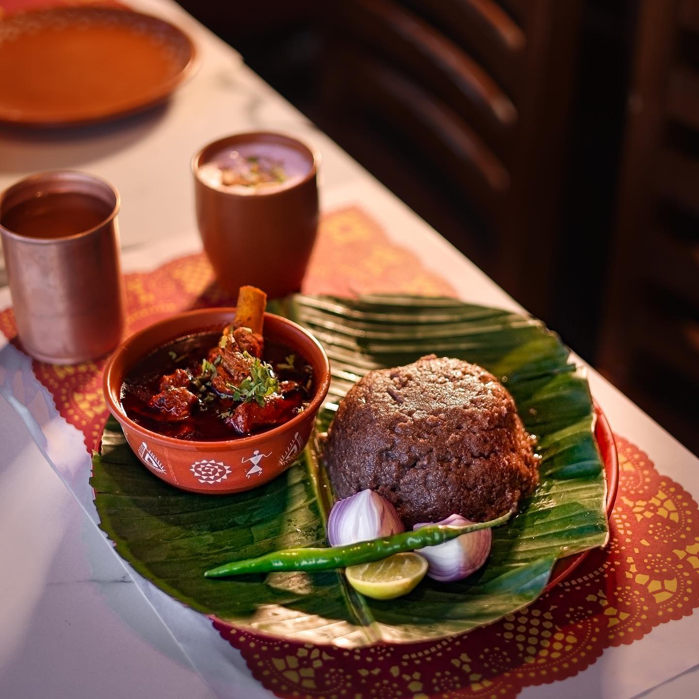 Ragi Sangati - Millet ball served with country chicken curry in traditional copper bowls